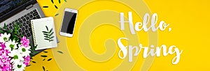 Hello Spring background with text inscription, holiday workspace with bouquet of flowers, yellow desktop