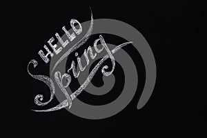 Hello spring. Seasonal photo, an inscription on a dark background of a slate wall or chalkboard. Place for text.