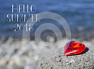 Hello Summer 2018 summertime background with decorative red heart on a pebble stone by the ocean coast.Travel or vacation concept.