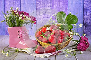 Hello summer concept. Ripe strawberries in a basket, a bouquet of wild flowers in a pink shoe