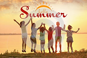 Hello Summer. Little children jumping near river at sunset, back view