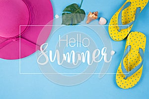 Hello Summer text on blue background, Yellow sandals with green tropical palm leaf and shell.