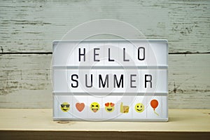 Hello Summer text in light box on wooden background