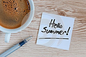 Hello summer - text at white sheet of notepad with morning coffee mug