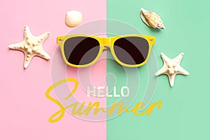 Hello Summer. Top view of yellow sunglasses, starfish, seashells and the text Hello Summer. Summer vacation concept