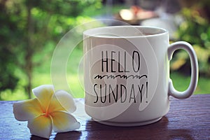 Hello Sunday. Beautiful relax Sunday with coffee drink. Welcome Sunday weekend. With text greeting on white cup of morning coffee. photo
