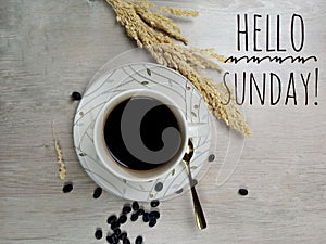 Hello Sunday. Text welcoming Sunday with background of a cup of blank morning coffee, spoon, roasted coffee beans decoration.