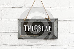 Hello thursday text on hanging board white brick ourdoor wall