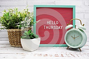 Hello Thursday text on Letter Board with alarm clcok and artificial plant decoration
