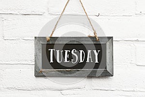 Hello tuesday text on hanging board white brick ourdoor wall