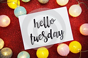 Hello Tuesday text on paper card top view on red bokeh background