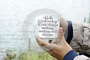 Hello Wednesday. If you change nothing, nothing will change. Wednesday concept with person holding coffee cup.