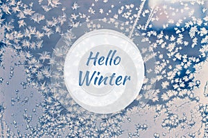 Hello winter greeting card with blue frosted window and frozen snowflakes closeup