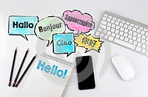 Hello word cloud in different languages of the world, background concept. Office desk table with computer, Smartphone and Notebook