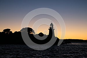 Hells gates lighthouse tasmania as silhouette in early morning sky