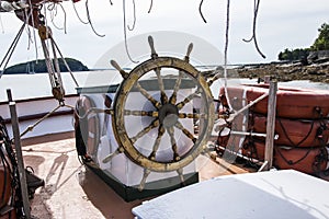 The helm of a wooden sailboat with porcupine island in the background