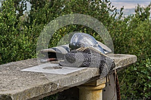 Helmet, chainmail and sword on a stone table