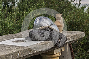 Helmet, chainmail and sword on a stone table