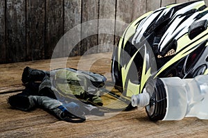 Helmet, gloves and water bottle - bicycle accessories on Wood.