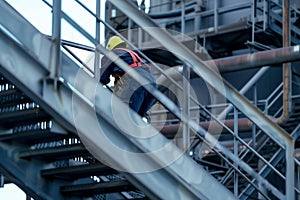 helmetclad worker climbing metal stairs in refinery structure