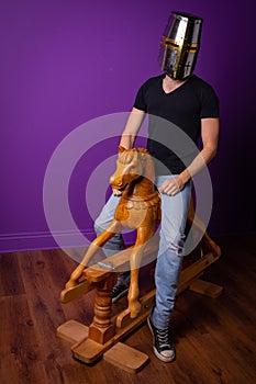 Helmeted knight on wooden rocking horse with purple wall and wooden floor