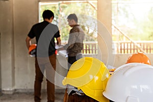 Helmets on desk in front of  Engineer or architect discussing with foreman in construction site