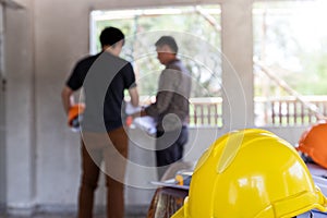 Helmets on desk in front of  Engineer or architect discussing with foreman in construction site