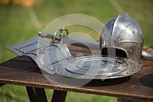 Helmets, Shields and Medieval Metallic Armors and Weapons, Outdoors on Wooden Table