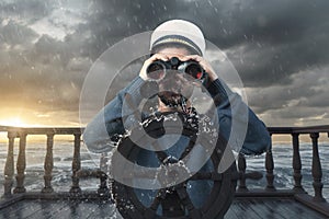 helmsman with binoculars and cap on stormy seas viewing the coast