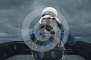 Helmsman with binoculars and cap viewing the coast and light tower photo