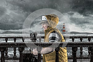 Helmsman with vest and cap struggle against storm in front of stormy sea