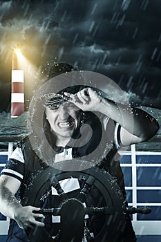 Helmsman with vest and cap struggle against storm in front of th