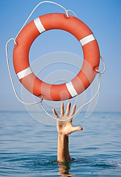 Help concept. Lifebuoy for drowning man's hand in