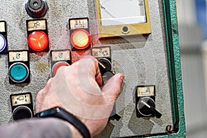 With the help of the control panel from the CNC machine, the man gives the command to the machine to process the part