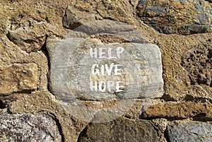 Help give hope symbol. Concept word Help give hope on beautiful big stone. Stone wall. Beautiful stone wall background. Business