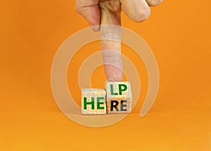 Help is here and support symbol. Businessman turns a cube and changes the word help to here. Beautiful orange background, copy