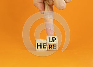 Help is here and support symbol. Businessman turns a cube and changes the word help to here. Beautiful orange background, copy
