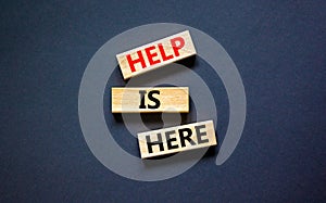 Help is here and support symbol. Concept words Help is here on wooden blocks on beautiful black table black background. Business,