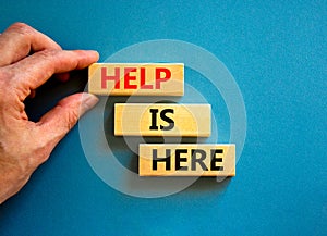 Help is here and support symbol. Concept words Help is here on wooden blocks on beautiful blue table blue background. Businessman