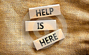 Help is here and support symbol. Concept words Help is here on wooden blocks on beautiful canvas table canvas background. Business