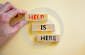 Help is here and support symbol. Concept words Help is here on wooden blocks on beautiful white table white background.