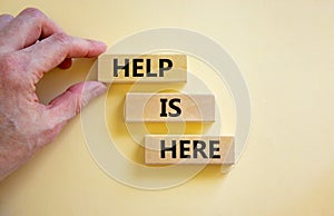 Help is here and support symbol. Concept words Help is here on wooden blocks on beautiful white table white background.
