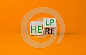 Help is here and support symbol. Turned a wooden cube and changed the word help to here. Beautiful orange background, copy space.