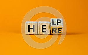 Help is here support symbol. Turned a wooden cube with concept word Help to Here. Beautiful orange table orange background, copy