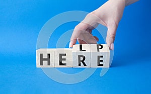 Help is here symbol. Businessman hand Turnes cubes and changes word Here to Help. Beautiful blue background. Business and Help is