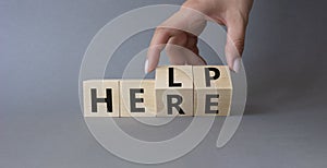 Help is here symbol. Businessman hand Turnes cubes and changes word Here to Help. Beautiful grey background. Business and Help is