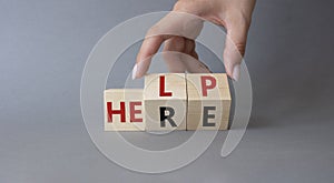 Help is here symbol. Businessman hand Turns cube and changes word Here to Help. Beautiful grey background. Business and Help is