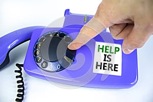 Help is here symbol. Old blue rotary dial telephone. Words `Help is here`. Beautiful white background. Businessman hand. Busines