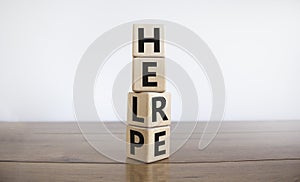 Help is here symbol. Turned cubes and changed the word help to here. Beautiful wooden table, white background, copy space.