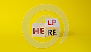 Help is here symbol. Turned wooden cube with words Here to Help. Beautiful yellow background. Business and Help is here concept.